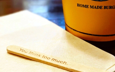 Wooden stick for stirring coffee with the phrase "you think too much" written on it
